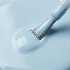 Primer plano del pincel con esmalte tradicional Morgan Taylor Not So Prince Charming, color Azules acabado Cream, textura del color