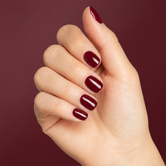 Mano con las uñas pintadas con esmalte tradicional Morgan Taylor Stand Out, color Borgoñas acabado Cream