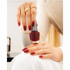 Mano sosteniendo el frasco de esmalte tradicional Morgan Taylor Good Gossip