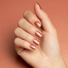 Mano con las uñas pintadas con esmalte tradicional Morgan Taylor Sunrise And The City, color Naranjas acabado Shimmer