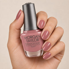 Mano sosteniendo el frasco de esmalte tradicional Morgan Taylor She's My Beauty, color Rosas acabado Cream, con las uñas pintadas a juego