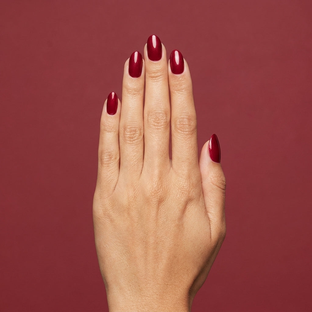 Mano con las uñas pintadas con esmalte tradicional Morgan Taylor Wonder Woman, color Rojos acabado Shimmer