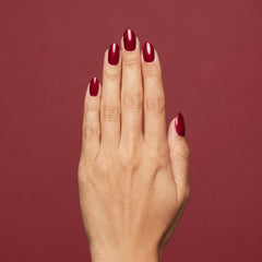 Mano con las uñas pintadas con esmalte tradicional Morgan Taylor Wonder Woman, color Rojos acabado Shimmer