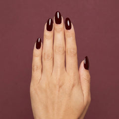 Mano con las uñas pintadas con esmalte tradicional Morgan Taylor From Paris With Love, color Borgoñas acabado Cream