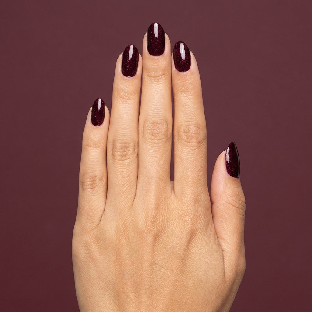 Mano con las uñas pintadas con esmalte tradicional Morgan Taylor Seal The Deal, color Morados acabado Glitter