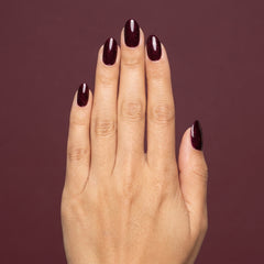 Mano con las uñas pintadas con esmalte tradicional Morgan Taylor Seal The Deal, color Morados acabado Glitter