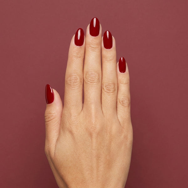 Mano con las uñas pintadas con esmalte tradicional Morgan Taylor Scandalous, color Rojos acabado Cream