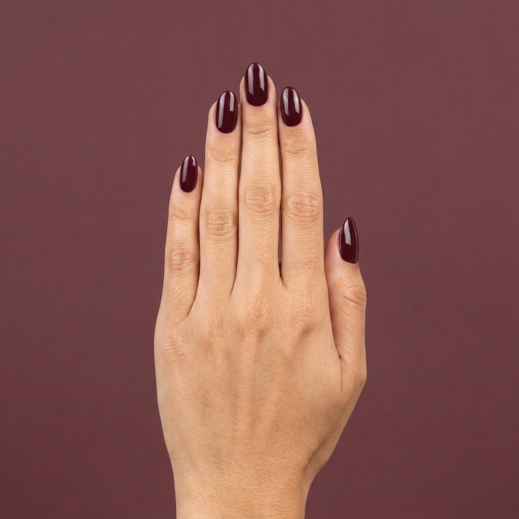 Mano con las uñas pintadas con esmalte tradicional Morgan Taylor A Little Naughty, color Borgoñas acabado Cream