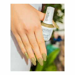 Mano con uñas doradas con glitter sosteniendo el frasco blanco Gelish Flash Glam Star Quality con tapa FLASH TO ACTIVATE