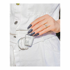 Mano con uñas gris grafito con glitter sosteniendo el frasco blanco Gelish Flash Glam Never Stop Glistening con tapa FLASH TO ACTIVATE
