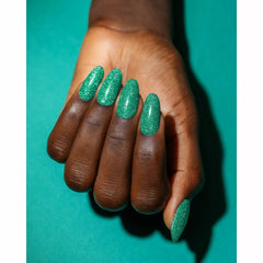 Mano con las uñas pintadas de verde menta con glitter Gelish Flash Glam Mint To Sparkle sobre fondo verde