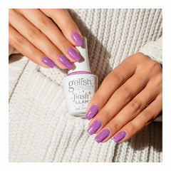 Manos con uñas lavanda con glitter sosteniendo el frasco blanco Gelish Flash Glam One Click At A Time con tapa FLASH TO ACTIVATE