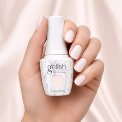 Mano sosteniendo el frasco de esmalte en gel Gelish Heaven Sent, color Blancos acabado Cream, con las uñas pintadas del mismo tono
