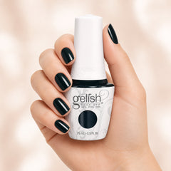 Mano sosteniendo el frasco de esmalte en gel Gelish I'm No Stranger To Love, color Negros acabado Cream, con las uñas pintadas del mismo tono