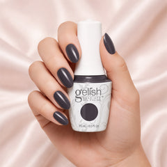 Mano sosteniendo el frasco de esmalte en gel Gelish Jet Set, color Negros acabado Cream, con las uñas pintadas del mismo tono