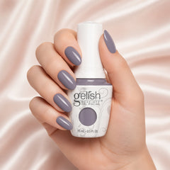 Mano sosteniendo el frasco de esmalte en gel Gelish Let's Hit The Bunny Slopes, color Mauves acabado Cream, con las uñas pintadas del mismo tono