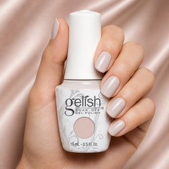 Mano sosteniendo el frasco de esmalte en gel Gelish Pretty Simple, color Blancos acabado Cream, con las uñas pintadas del mismo tono