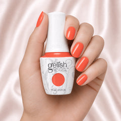 Mano sosteniendo el frasco de esmalte en gel Gelish Rockin' The Reef, color Naranjas acabado Cream, con las uñas pintadas del mismo tono