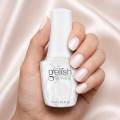 Mano sosteniendo el frasco de esmalte en gel Gelish Sweet On You, color Blancos acabado Cream, con las uñas pintadas del mismo tono