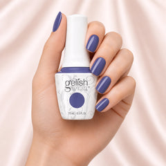 Mano sosteniendo el frasco de esmalte en gel Gelish Up In The Blue, color Morados acabado Cream, con las uñas pintadas del mismo tono